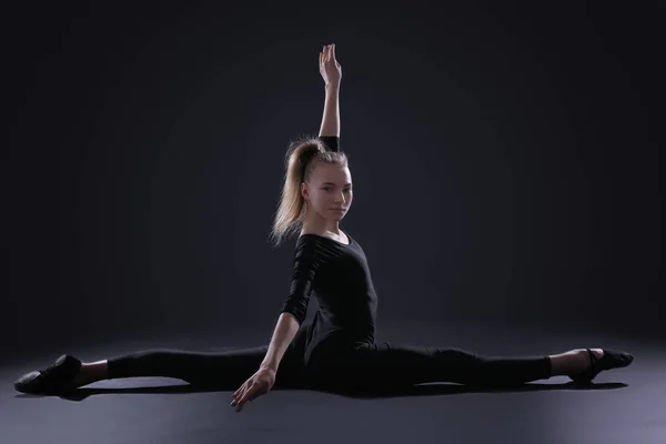 Młoda dziewczyna robi Gimnastyka na ciemnym tle — Zdjęcie stockowe