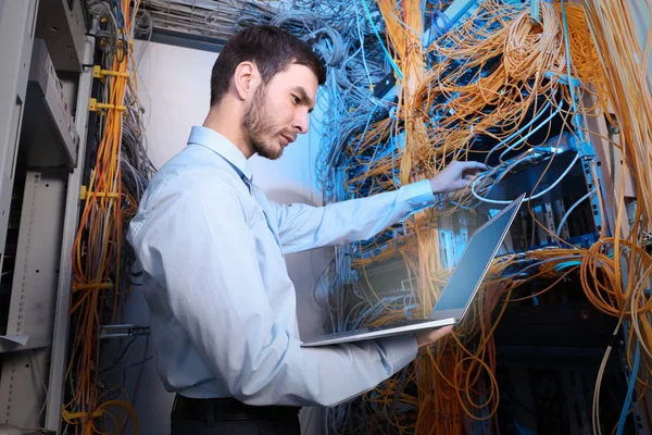 Handsome young engineer with laptop in server room — Stock Photo, Image