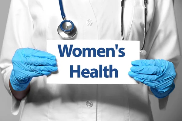 Doctor holding paper with text WOMEN'S HEALTH — Stock Photo, Image