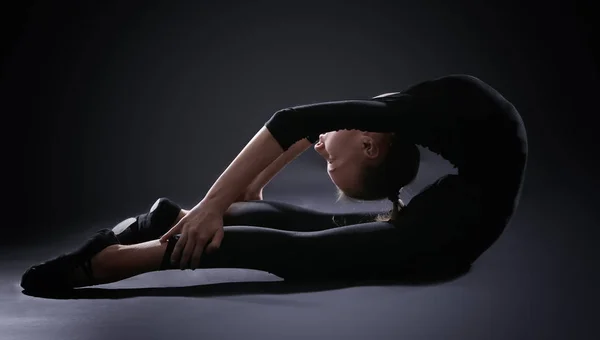 Chica joven haciendo gimnasia sobre fondo oscuro —  Fotos de Stock