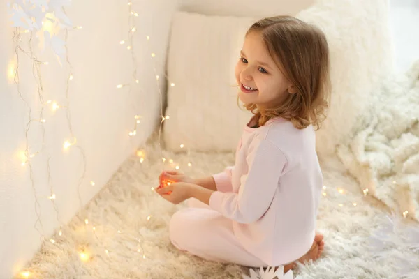 Menina bonito brincando com guirlanda em casa — Fotografia de Stock