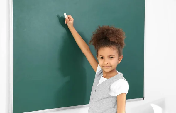 Portret van schoolmeisje schrijven op blackboard — Stockfoto