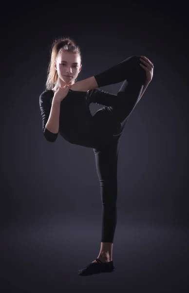 Giovane ragazza che fa ginnastica su sfondo scuro — Foto Stock