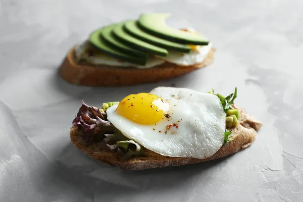 Tostadas con huevos fritos y aguacate sobre mesa gris — Foto de Stock