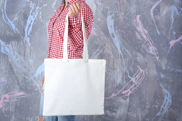 Jeune femme avec sac à provisions sur fond de couleur — Photo