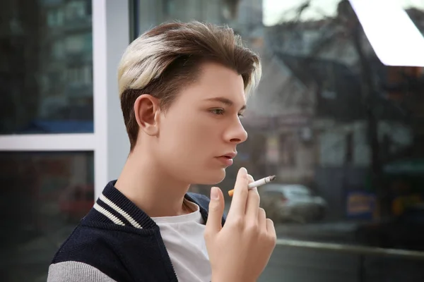 Adolescent garçon fumer sur fenêtre fond — Photo