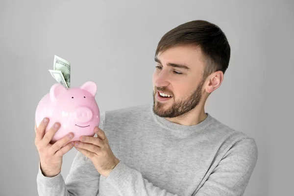 Homem segurando porquinho banco com dinheiro — Fotografia de Stock
