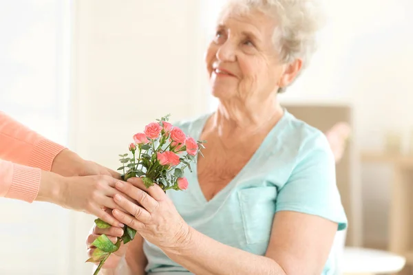 Giving flowers to old woman Stock Picture