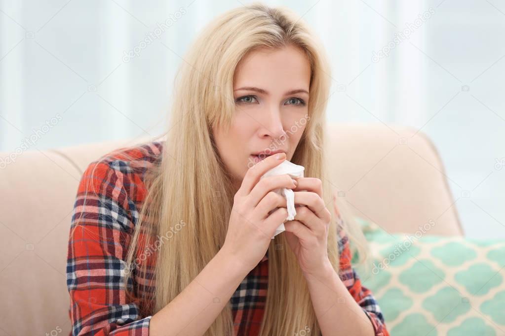 Young woman with allergy sitting on sofa at home