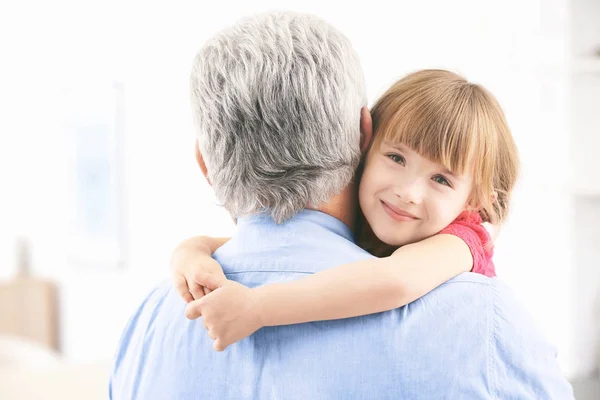 Chica abrazando abuelo en casa — Foto de Stock