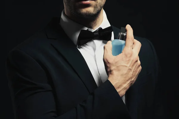 Bello giovane uomo utilizzando profumo — Foto Stock