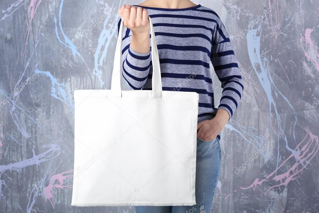 Young woman with shopping bag on color background