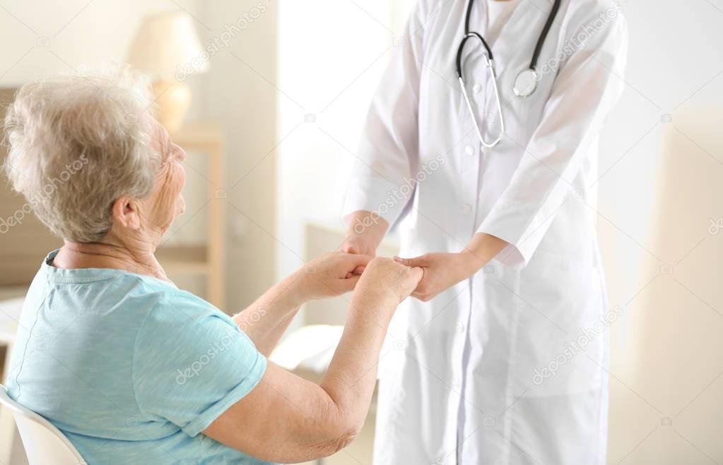 doctor holding hands of elderly woman 