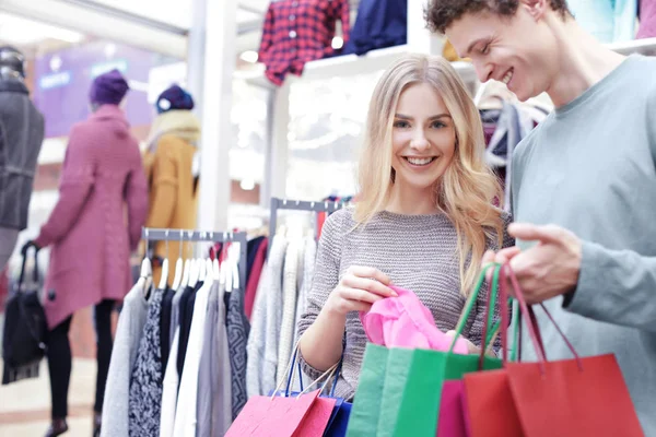 Glückliches junges Paar kauft Kleidung in modernem Geschäft — Stockfoto