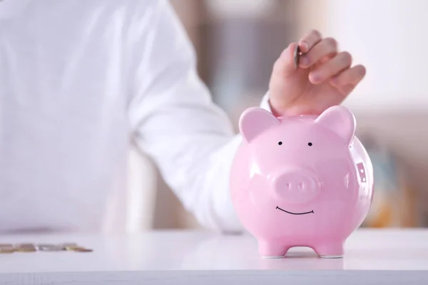 Homem colocando moeda em Piggy Bank — Fotografia de Stock