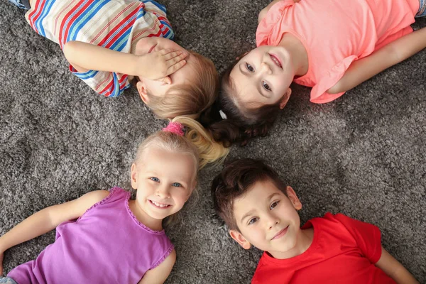 Милі маленькі діти лежать на килимі вдома — стокове фото