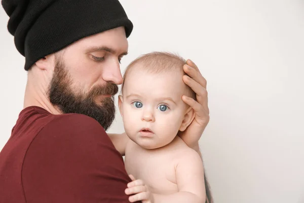 Bello tatuato giovane uomo tenendo carino piccolo bambino su sfondo chiaro — Foto Stock