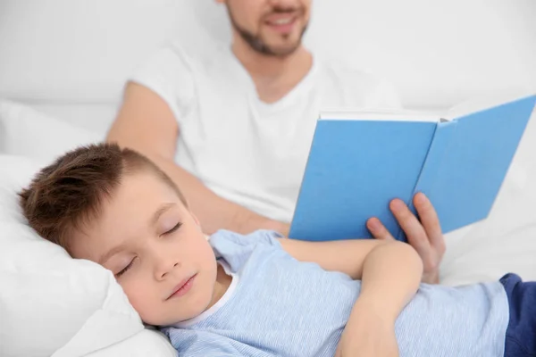 Sovande pojke och far läser bok — Stockfoto