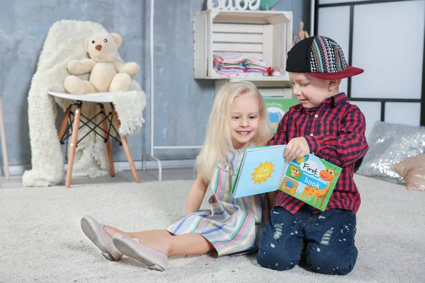 Cute funny children sitting on carpet with book — Stock Photo, Image