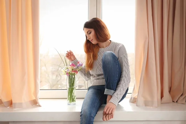 Schöne junge Frau auf der Fensterbank — Stockfoto
