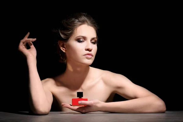 Beautiful young woman with bottle of perfume — Stock Photo, Image