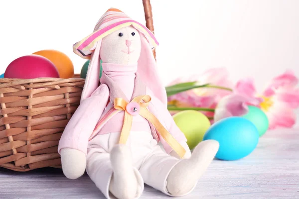 Toy rabbit sitting near Easter basket — Stock Photo, Image