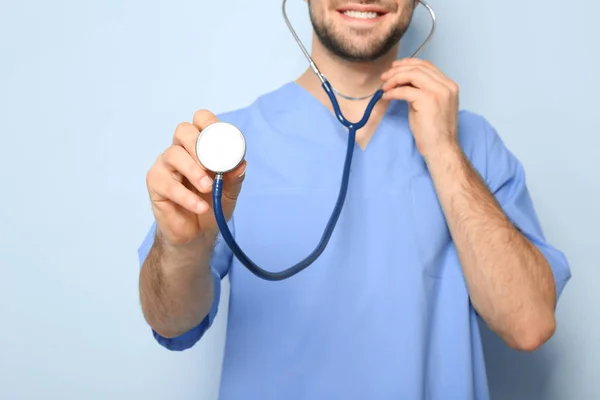 Young medical assistant with stethoscope on color background, closeup Stock Photo