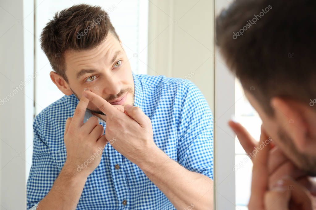 Young man putting contact lenses  