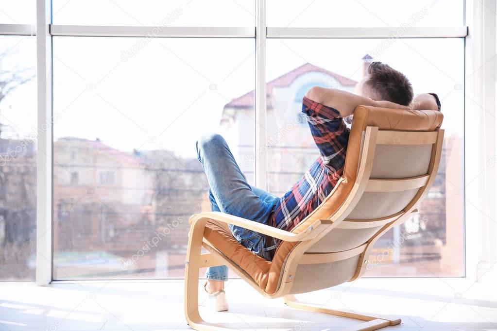 Happy young man resting in armchair 