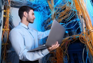sunucu odası içinde laptop ile genç mühendis