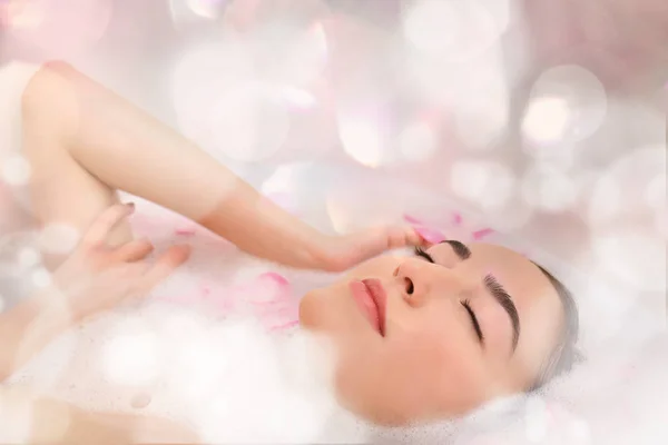 Jovem mulher atraente relaxando no banho com espuma e pétalas, close-up — Fotografia de Stock