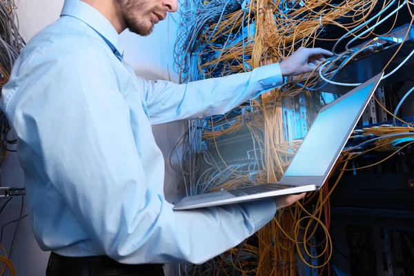 Joven ingeniero con portátil en la sala de servidores — Foto de Stock