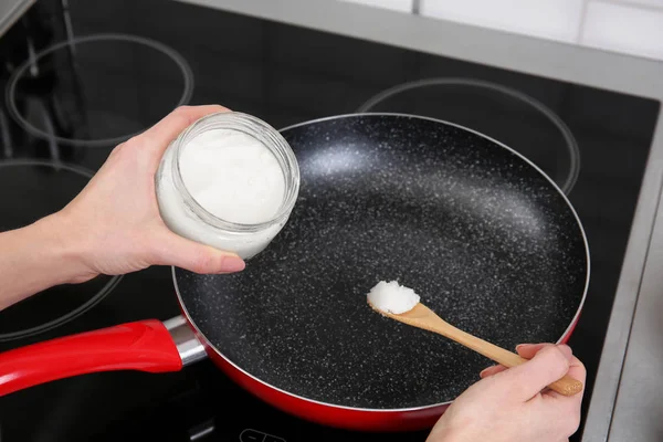 Putting coconut oil into frying pan — Stock Photo, Image