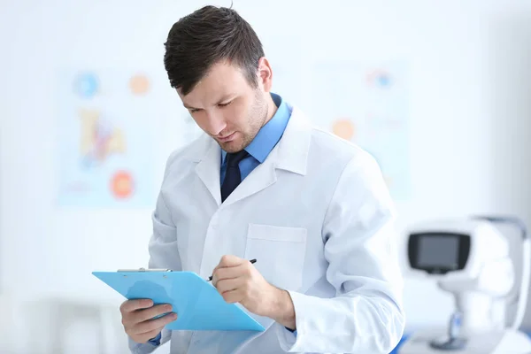 Joven médico con portapapeles en el consultorio —  Fotos de Stock