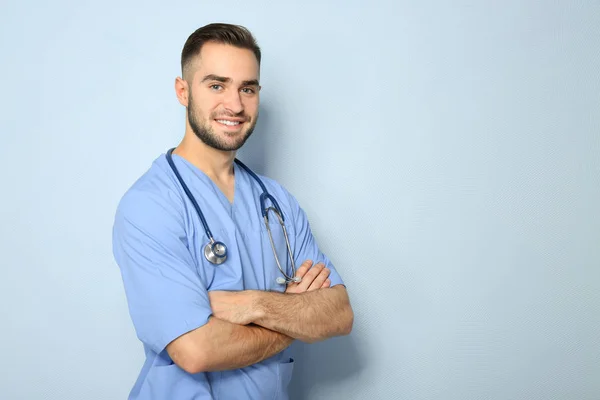 Young medical assistant with stethoscope on color background — Stock Photo, Image