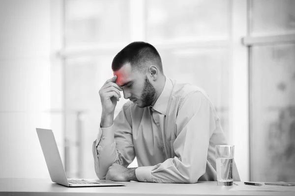 Молодой человек, страдающий головной болью во время работы в офисе — стоковое фото