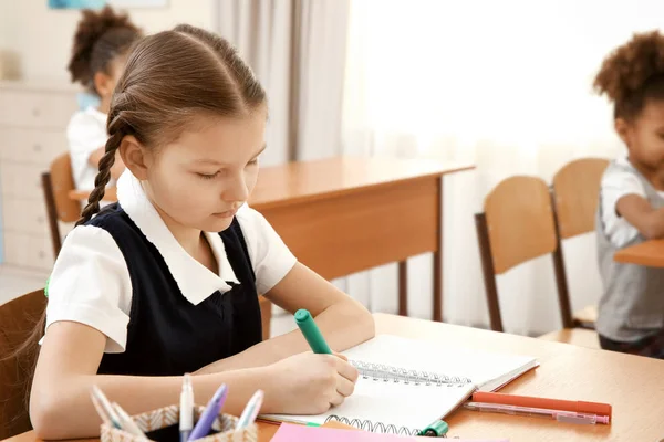 Beautiful elementary schoolgirl studying in classroom — Stock Photo, Image
