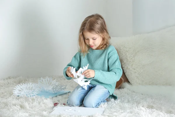 Menina cortando flocos de neve de papel — Fotografia de Stock