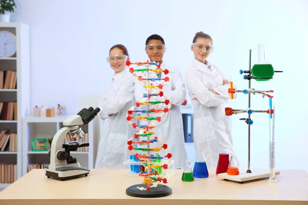 Робоче місце з ДНК моделі та учнів, стоячи в класі хімії — стокове фото