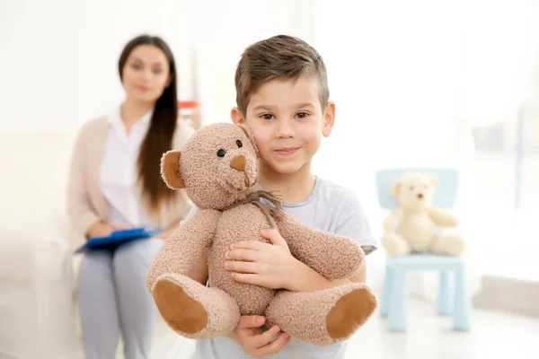 Little boy with teddy bear and child psychologist on background — Stock Photo, Image