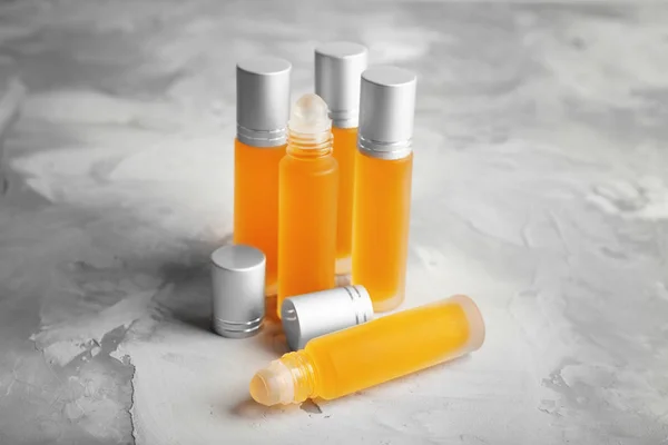 Lahvičky s parfémy na šedém povrchu — Stock fotografie