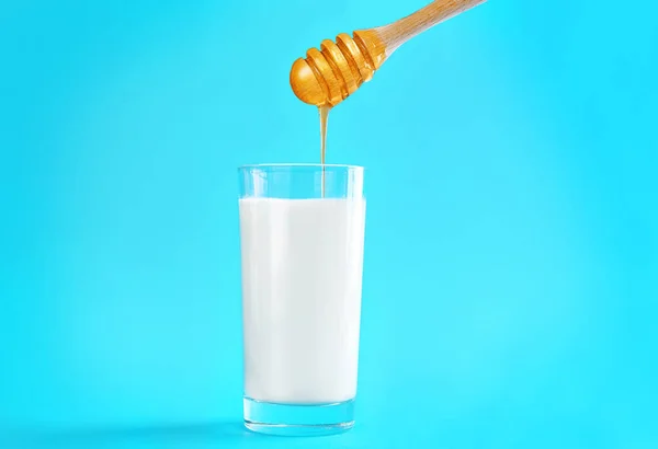 Pouring honey into glass of milk — Stock Photo, Image