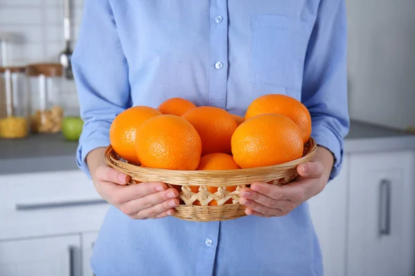 Mulher com cesta de vime cheia de laranjas — Fotografia de Stock