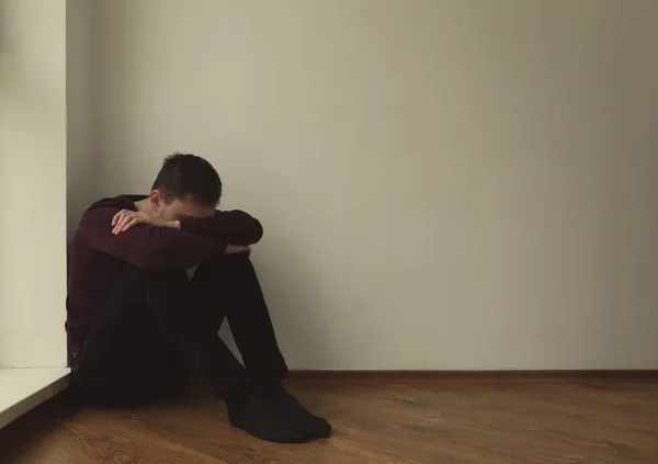 Hombre apuesto deprimido sentado en el suelo en casa — Foto de Stock