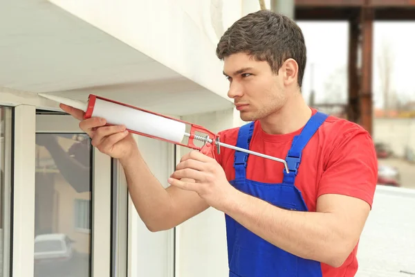 Worker sealing joints of office window — Stock Photo, Image