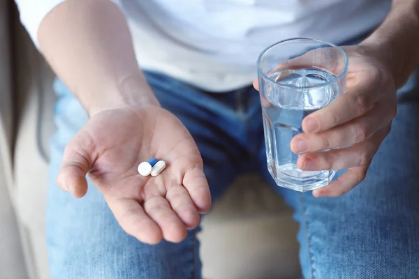 Young man with pills and water — Stock Photo, Image