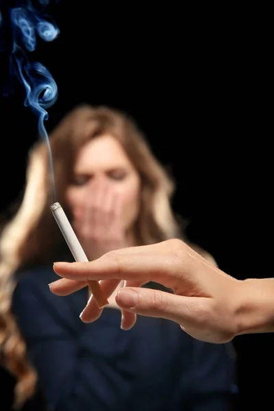 Woman covering face from cigarette smoke