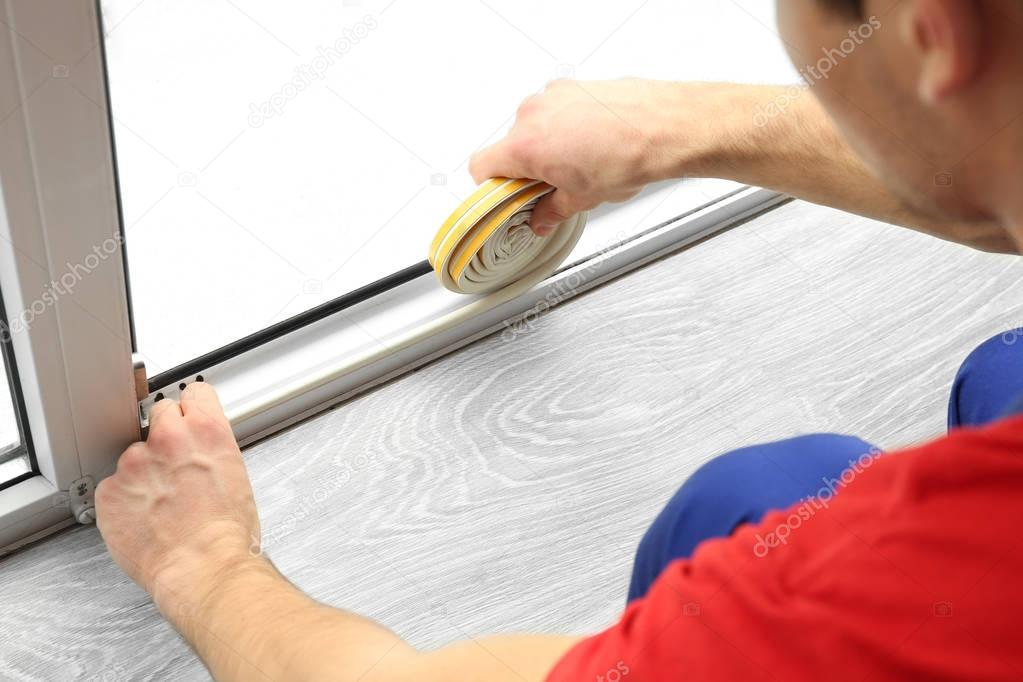 worker applying rubber strip onto window