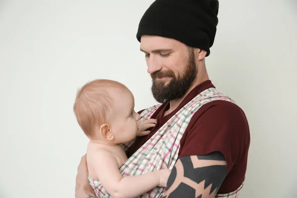 Şirin Bebek ışık arka plan üzerinde tutarak dövmeli yakışıklı genç — Stok fotoğraf