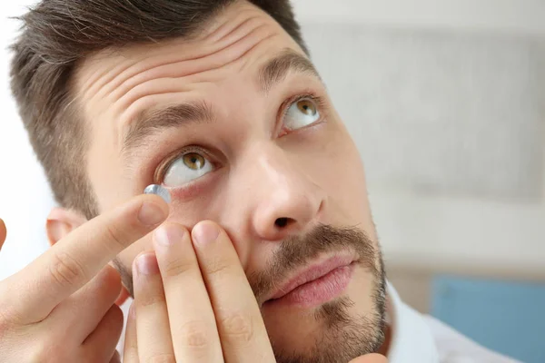 Mladý muž uvedení kontaktní čočky — Stock fotografie